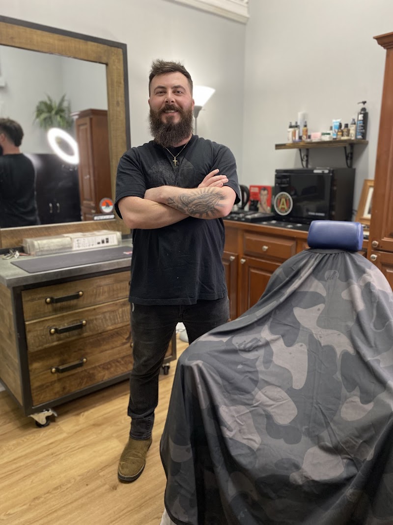 Dusty standing in his barbershop — tattooed, bearded, confident